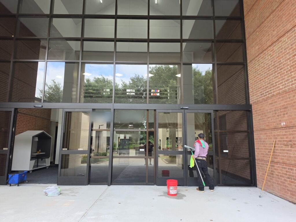Technician cleaning entrance glass at a commercial campus building