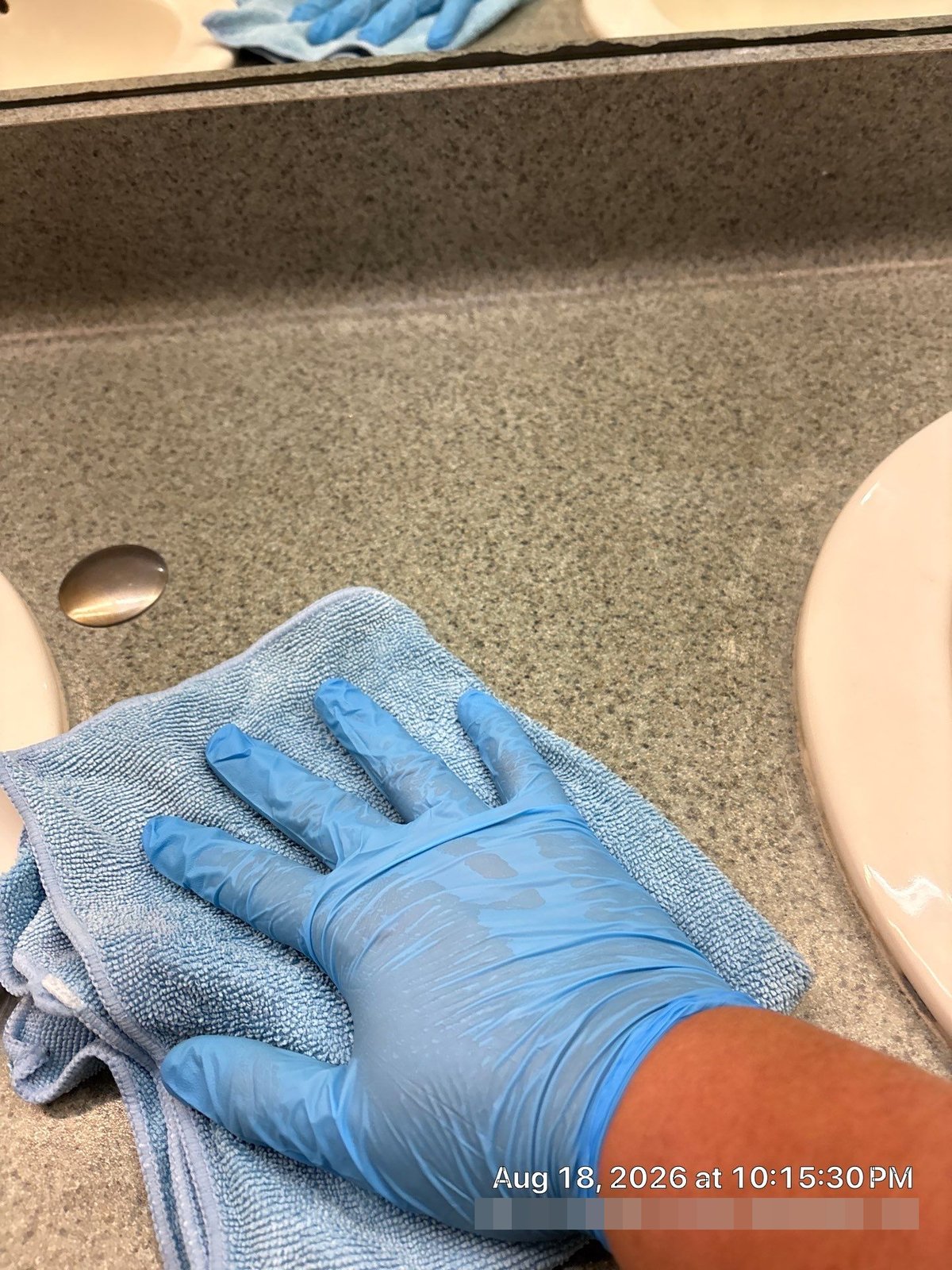 Cleaning technician wiping restroom counter with microfiber cloth