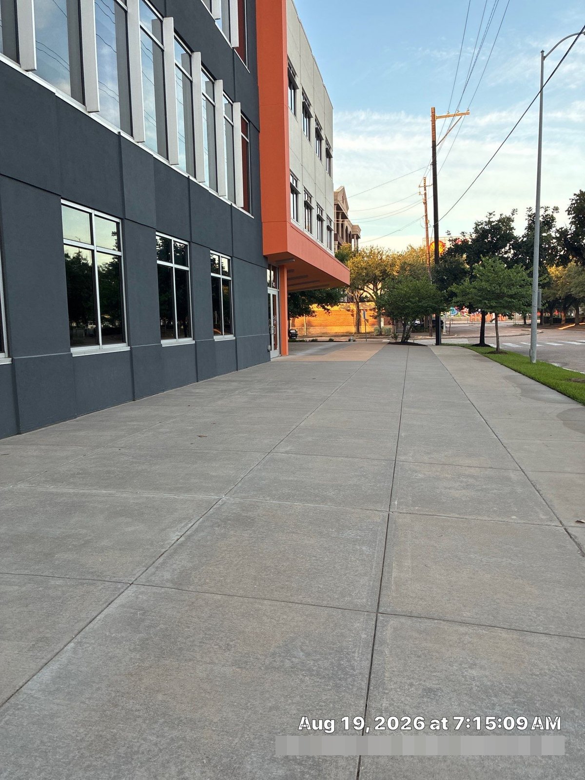 Clean swept sidewalk at commercial building entrance at sunrise