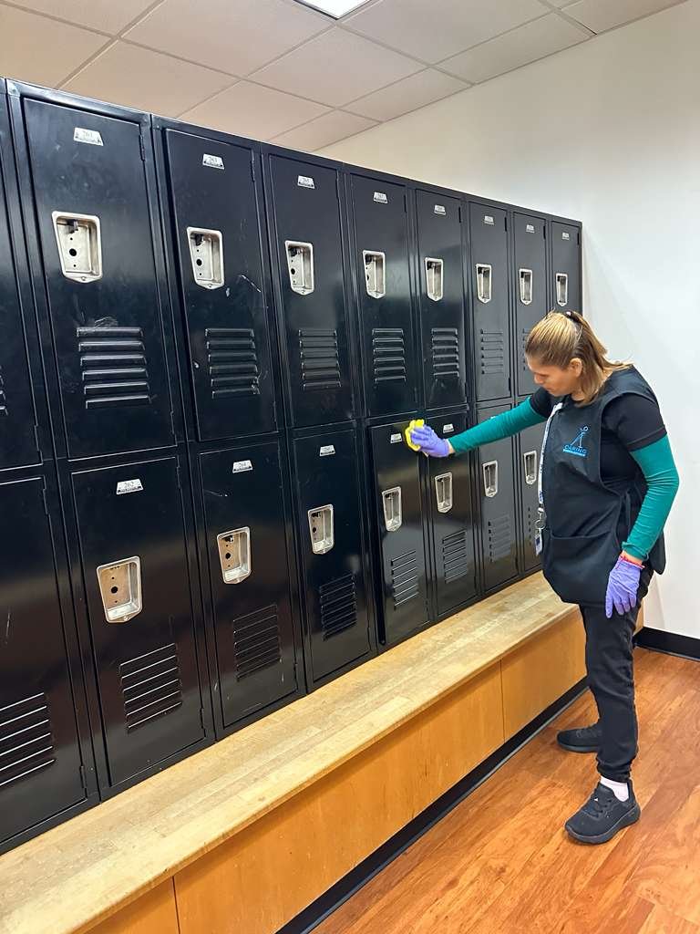 Wiping down gym lockers in a school athletic facility