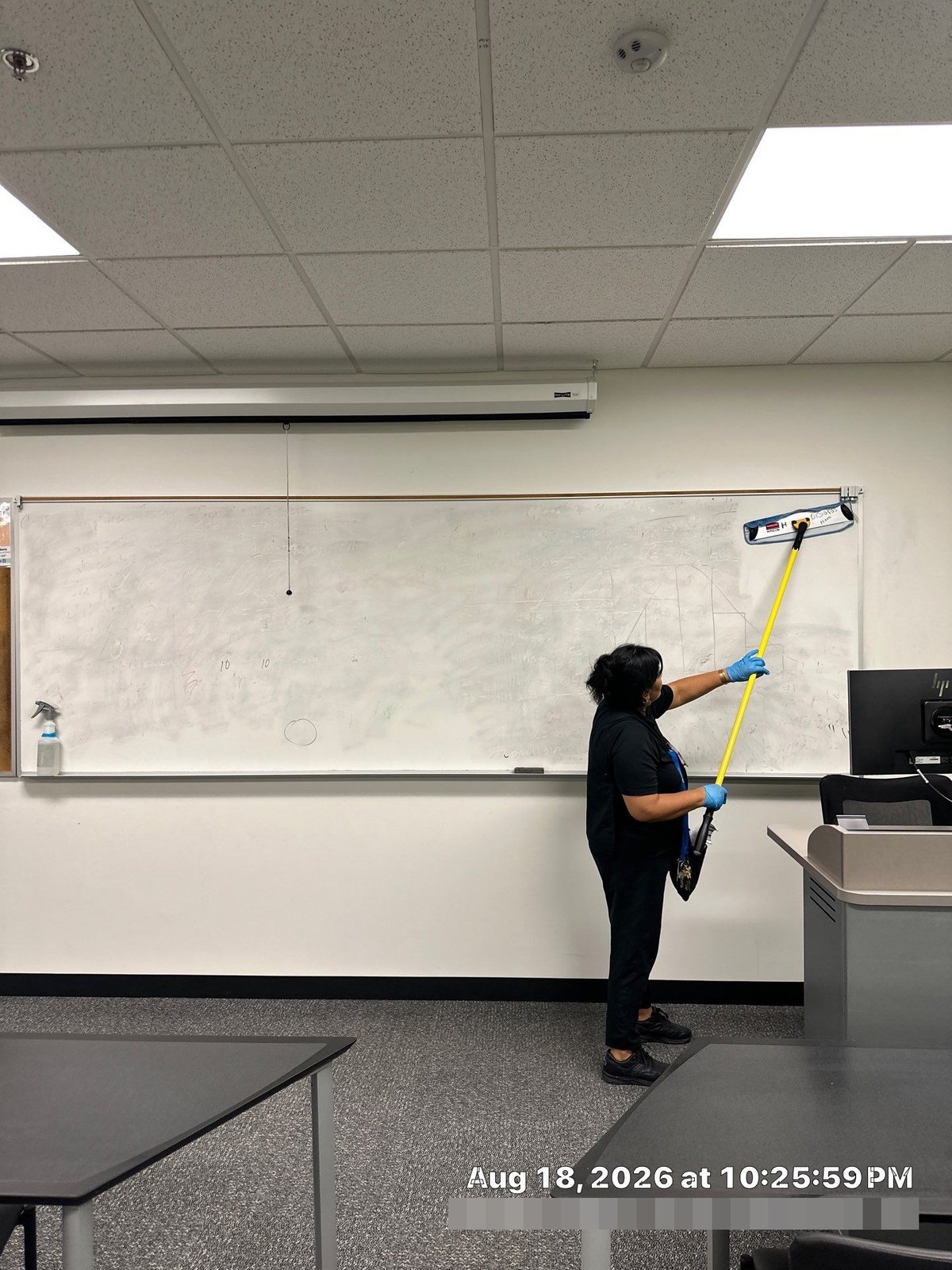 Technician detailing whiteboard in college classroom