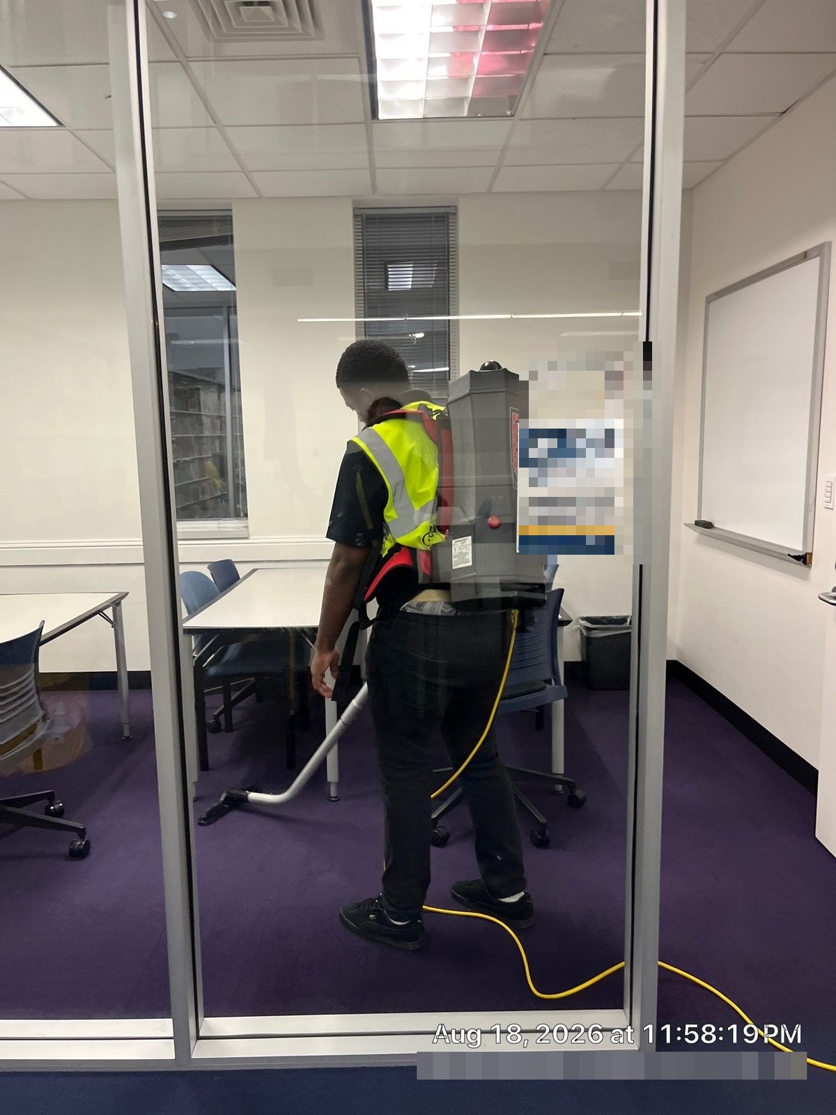 Technician vacuuming study room carpet at night