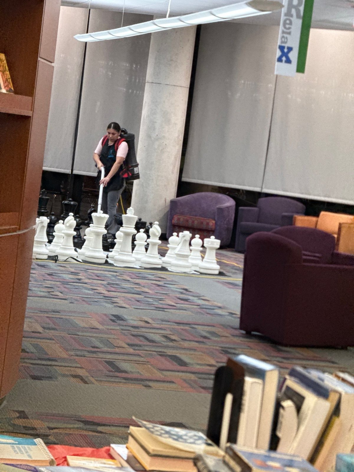 Technician vacuuming library carpet with backpack vacuum