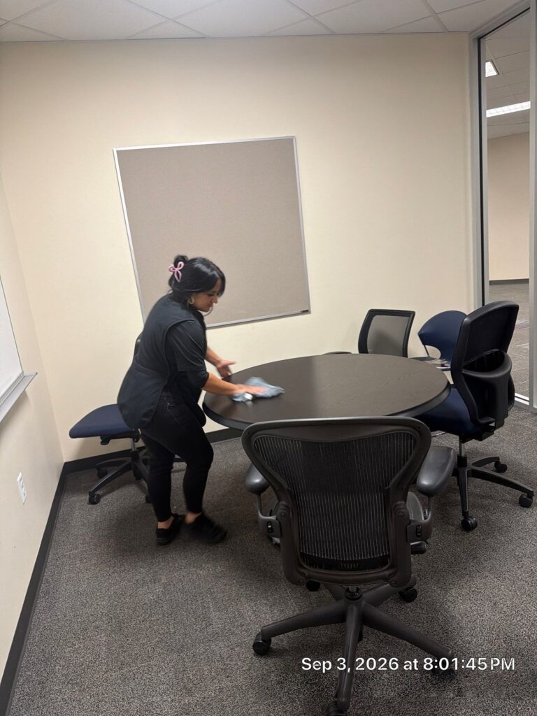 Caring Commercial Cleaning team member cleaning a conference room table in a Houston office building